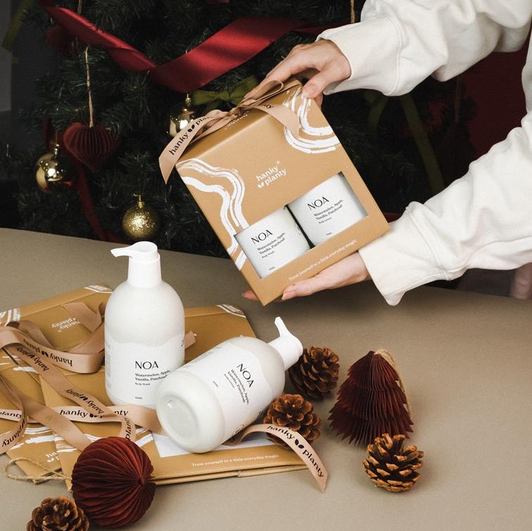 NUO Duo gift set featuring one NOA natural body wash and one NOA body lotion in eco-friendly brown box packaging with Hanky Planty branding, displayed alongside unboxed bottles, pinecones, and festive decorations.