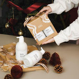 NUO Duo gift set featuring one NOA natural body wash and one NOA body lotion in eco-friendly brown box packaging with Hanky Planty branding, displayed alongside unboxed bottles, pinecones, and festive decorations.