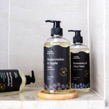 Hanky Planty natural body wash collection, featuring 500ml Watermelon & Apple, Rosemary & Aloe Vera, and Raspberry & Macadamia variants in black-labeled pump bottles with golden liquid, displayed in a tiled bathroom.