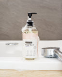 Hanky Planty Antibacterial Body Wash with Vitamin E, 500ml pump bottle, covered in foamy lather, placed on a bathroom sink beside a shower head.